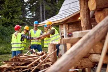 Takım çalışması genç inşaat işçileri. İnşaat işçileri birlikte ahşap ev üzerinde çalışıyorlar.,