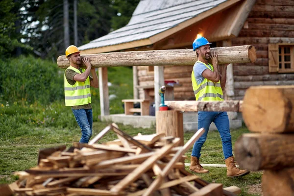 Dos Jóvenes Constructores Masculinos Llevan Madera Sitio Construcción Cabaña Bosque — Foto de Stock