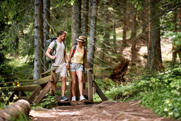 Cheerful Young Couple Walking Forest Trail Bridge Holding Hands Talking — Stock Photo, Image