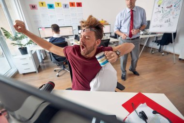 Yorgun bir erkek çalışan ofisteki üniformalı bir ortamda iş yerinde uyuyakalmış. Çalışanlar, iş, ofis