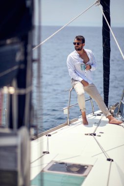 Yatta tek başına yelken açan hoş görünümlü bir adam, lüks yaşam tarzı konsepti.