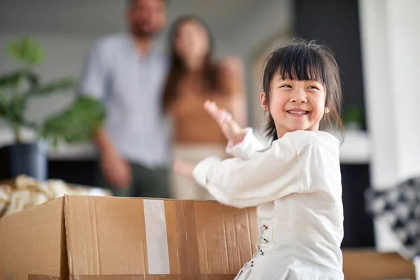 可爱的亚洲小女孩拍打纸板箱 在后台和父母一起玩 — 图库照片