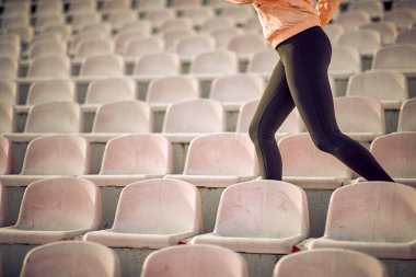 Formda bir kadın gündüz vakti tribünde tek başına çalışıyor.