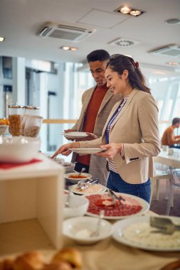 Genç iş adamları, kantindeki rahat atmosferde lezzetli yiyeceklerle kendi kendilerine servis yapıyorlar. İş, insanlar, şirket.