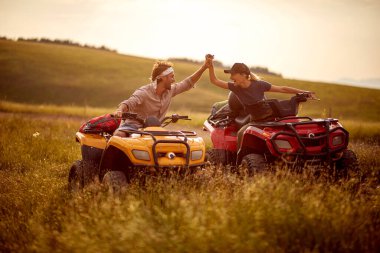 Genç bir çift, doğada güneşli bir günde dörtlü sürerken eğleniyor. Binicilik, doğa, ilişki, aktivite