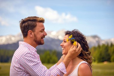 Kadın kulağının arkasına çiçek koyan bir adam. Doğada bir çift. Eğlence, birliktelik, doğa konsepti..
