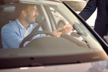 Araba satıcısı, oto satış salonundaki satıcıdan yeni bir arabanın anahtarını alıyor.