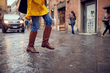 Şehirde yağmurda aceleyle yürüyen genç bir kızın bacakları yakın plan. Yürü, yağmur, şehir