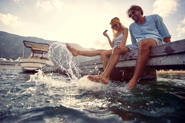 Genç çift flört ediyor ve gölde sallanan bacaklardan zevk alıyor.