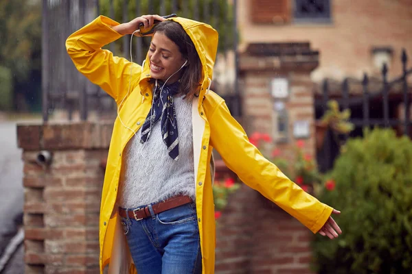 Sarı yağmurluk giymiş neşeli genç bir kadın, müzik dinlerken ve yağmurlu bir günde şehirde iyi bir ruh hali içinde yürürken kendinden geçiyor. Yürü, yağmur, şehir