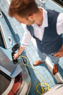 Kafkas işçisi şarj istasyonunda elektrikli arabasını şarj ediyor.