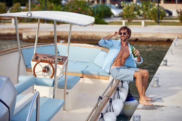 桟橋でヨットに座ってビールと若い魅力的な男性 夏の楽しみ レジャー ライフスタイルのコンセプト — ストック写真