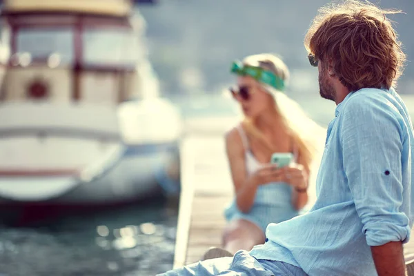 Young Couple Sitting Water Wooden Jetty Woman Phone Man Looking — Stockfoto