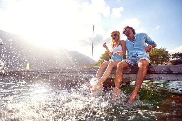 Attractive Couple Laughing While Sitting Jetty Water Splashing Water Legs — Stock Photo, Image