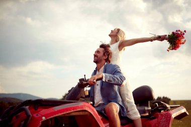 Mutlu yeni evliler doğada dörtlü araba kullanırken; kırsal evlilik kavramı