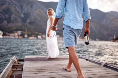 Şarap ve bardakla dolu bir damat, deniz kenarında romantik bir randevu. Balayında yeni evli bir çift. Düğün, balayı, aşk konsepti