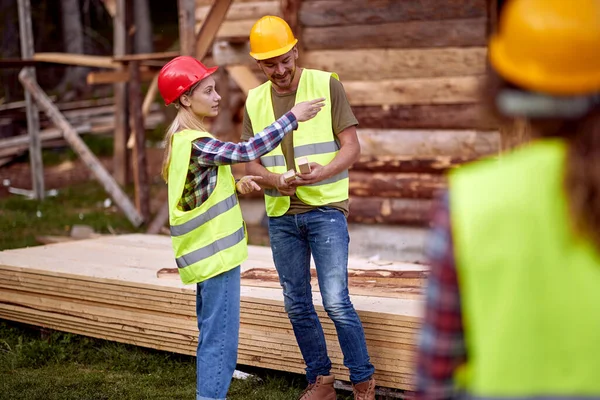 Genç inşaat işçileri birlikte bir şantiyede dağ evi inşa ediyorlar.