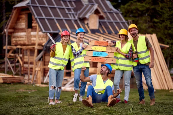 Young construction workers team working on a mountain cottage project together; Renovation concept