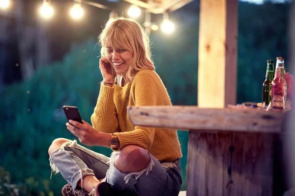소녀는 아름다운 저녁에 현관에서 스마트폰으로 메시지를 읽으면서 흥분합니다 — 스톡 사진