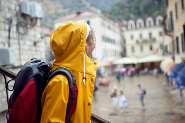 黄色のレインコートを着た魅力的な女性が雨の日に旧市街を歩き回り — ストック写真