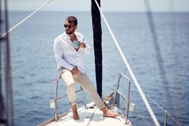 Casual attractive man sailing alone on the yacht; Luxurious lifestyle concept