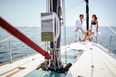 Genç bir çift sohbet ediyor ve güzel güneşli bir denizde gezinti yaparken yatın pruvasında fotoğraf için poz veriyor. Yaz, deniz, tatil, ilişki