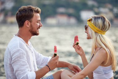 Yazın rıhtımda karpuz yiyen neşeli bir çift. Seyahat, aşk, eğlence, birliktelik, yaşam tarzı konsepti.