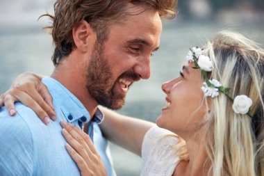 Beyaz elbiseli güzel, gülümseyen gelin erkeğinin kucaklamasının tadını çıkarıyor.