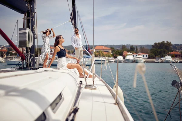 Bir grup genç arkadaş, deniz kenarında güneşli bir günde yatta poz veriyorlar. Yaz, deniz, tatil, arkadaşlık