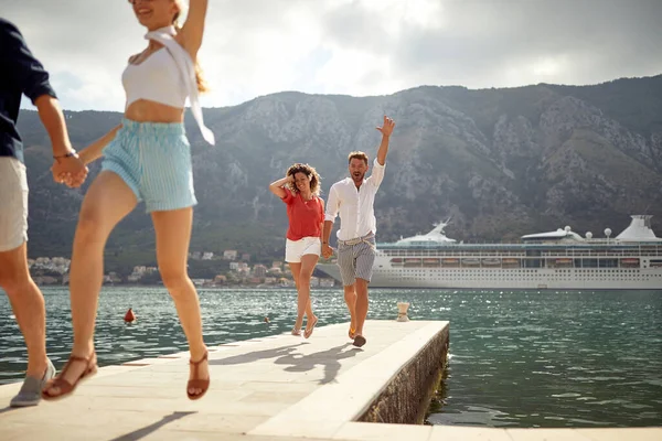 Two Couples Holding Hands Running Pier Sea Cruiser City Mountains — Stok fotoğraf