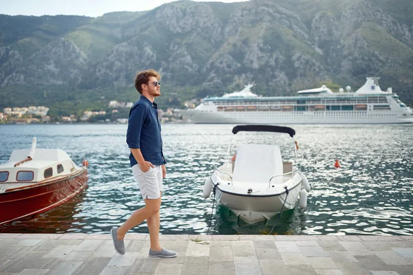 Genç adam tatilde rıhtımda yürüyor..