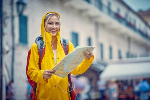 Fiatal Mosolygós Sárga Esőkabáttal Térképpel Utcán Miközben Élvezi Sétát Városban — Stock Fotó