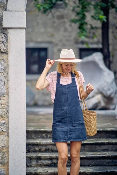Genç bir kadın güzel bir günde deniz kenarında bir tatil sırasında eski şehirde yürüyüş yapıyor. Tatil, deniz kenarı, turist