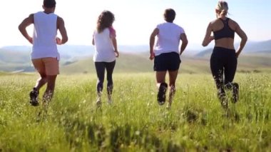 Bir grup insan çayırda koşuyor. Spor, çimen, koşmak, sağlıklı yaşam tarzı konsepti. 