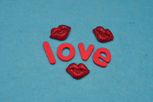 愛という言葉が青い背景に隔離された3つのキャンディーの形の唇 — ストック写真