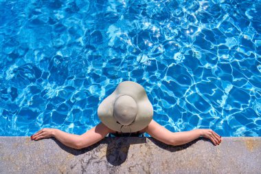 Şapkalı bir kız güzel bir havuzda dinleniyor. Tatil kavramı