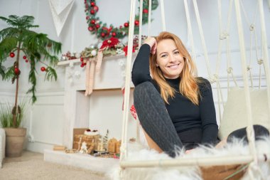 Yeni yıl tatilinde şöminenin arka planında kameraya poz veren kızıl saçlı kız. Sıradan bir portre.