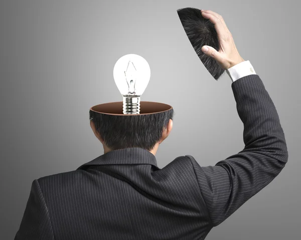 Single lighting lamp inside businessman head in gray background — Stock Photo, Image