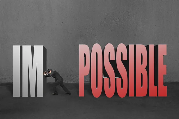 Businessman push word "impossible" im away, to make it possible in concrete wall background. — Stock Photo, Image