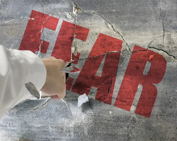 Punching, break concrete wall with word fear on it and small pie — Stock Photo, Image