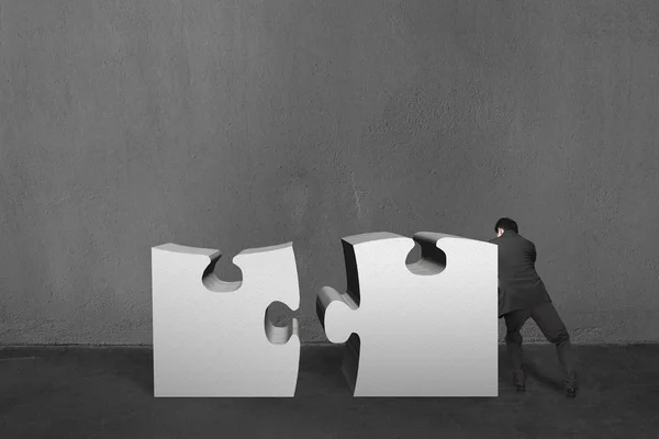 Empresário empurrar dois enigmas pesados juntos em bac parede de concreto — Fotografia de Stock