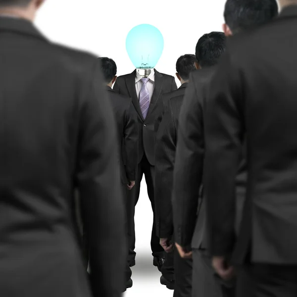 Un uomo d'affari con la testa lampadina di illuminazione in piedi di fronte a gro — Foto Stock