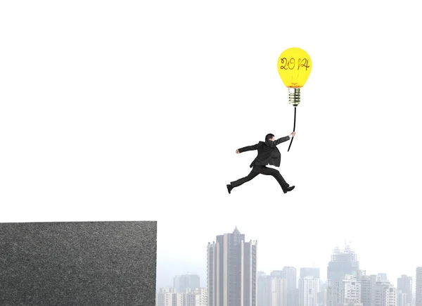 Businessman jumping from bulding top to catch glowing lamp ballo — Stock Photo, Image