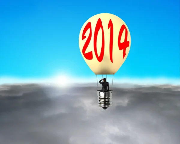 Man taking lamp balloon floating over clouds, looking at sun — Stock Photo, Image