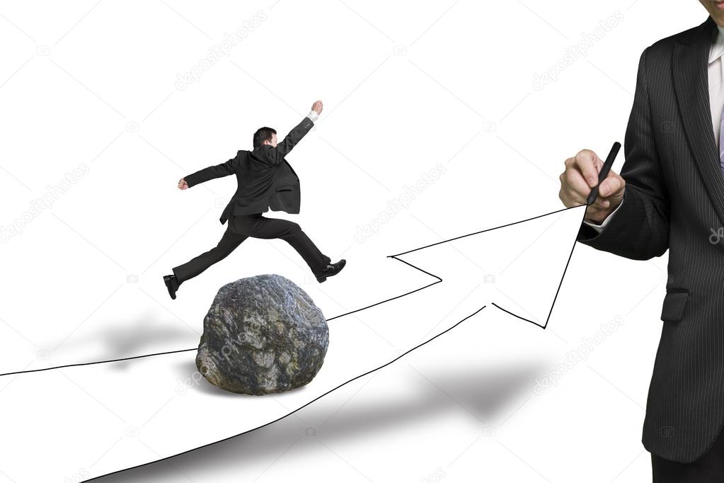 Businessman drawing road with arrow, another jumping over rock
