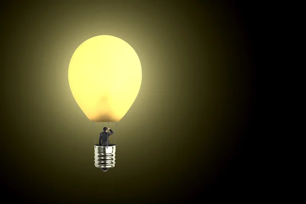 Человек берет светящийся шар лампы глядя на далекое место — стоковое фото