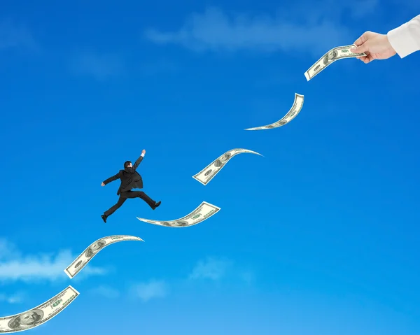 Hombre de negocios saltando sobre el dinero con la mano sostenga uno —  Fotos de Stock