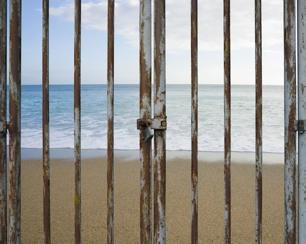 Ржавая запертая дверь с пляжным океаном и небом — стоковое фото