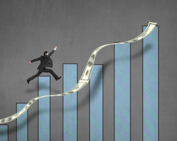 Бизнесмен прыгает на растущий денежный тренд с графиком на стене — стоковое фото