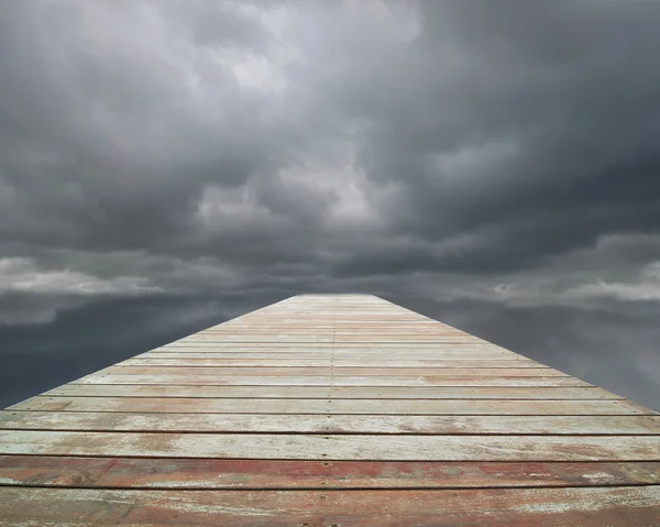 Wooden way with cloudy sky and spot in front — Stock Photo, Image